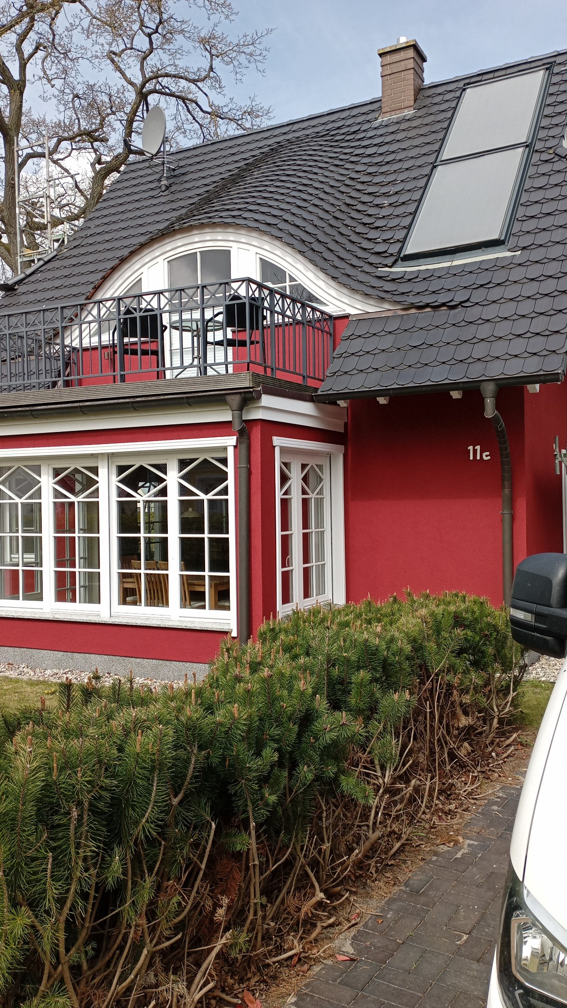 Rotes Haus mit Walmdach, großen Fenstern und Solarpanelen